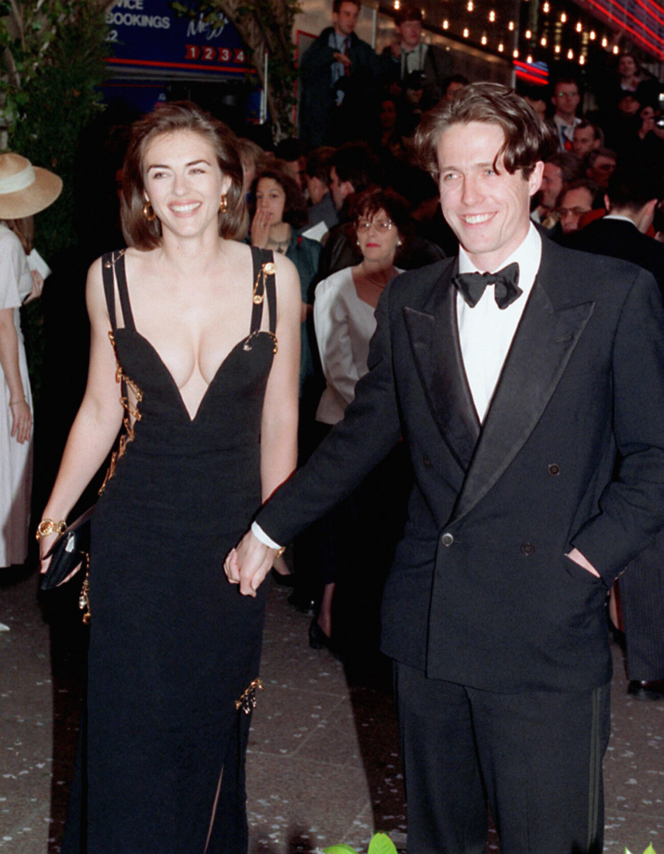 Actor Hugh Grant, star of 'Four Weddings and a Funeral', arrives for the charity premiere of the film with his girlfriend, actress Elizabeth Hurley, at the Odeon Cinema in London's Leicester Square. Miss Hurley wears a revealing Versace evening dress. *27/4/99 Hollywood superstar Julia Roberts jetted into Britain to the premiere of her latest movie, Notting Hill, but was upstaged by co-star Hugh Grant's girlfriend Liz Hurley and her dazzling dress. Model Hurley, the face of Estee Lauder, repeated the same trick she pulled off five years ago for the launch of Four Weddings And A Funeral when she wore a stunning Versace frock. For Notting Hill, the follow up to Four Weddings, she turned heads in a sheer and shimmering backless outfit, which was split from ankle to thigh and was again Versace. (Photo by Michael Stephens - PA Images/PA Images via Getty Images)